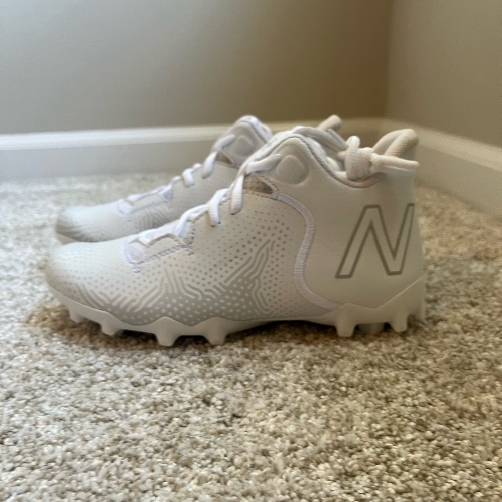 Brand NEW bright white New Balance Freeze youth athletic cleats. Never worn!